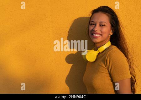Junge selbstbewusste Frau, die mit legerer Kleidung und Platz zum Kopieren steht. Erfolgreiche lächelnde Frau mit großem Lächeln, die auf die Kamera schaut. Schön positiv wo Stockfoto