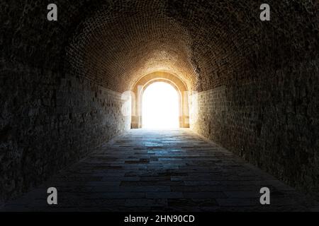 Der dunkle Tunnel in der Katakombe. Licht am Ende des Tunnels Stockfoto