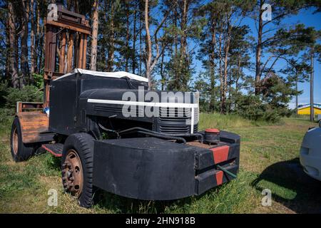 Ein rostiger alter Gabelstapler in einem Pinienwald. Ein blauer Himmel im Hintergrund Stockfoto