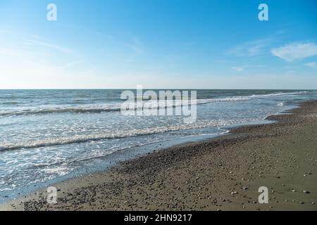 Sandstrand mit Kieselsteinen, Meereswellen Rollen an einem sonnigen Tag auf den Strand Stockfoto