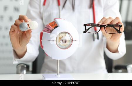 In weiblichen Händen Brille für das Sehen neben dem Modellauge, verschwommen Stockfoto