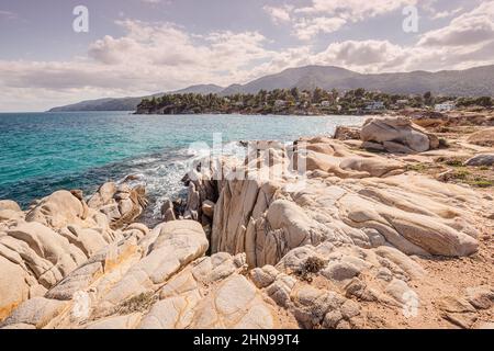 Blick auf die malerische Szene von Meereswellen, die auf die Felsen einer malerischen Insel in der Nähe des Ferienortes in der Region Chalkidiki krachen Stockfoto