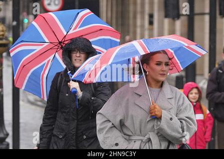 Frauen unter ihren Sonnenschirmen in Westminster, London, während einer Regendusche in der Hauptstadt. Bilddatum: Dienstag, 15. Februar 2022. Stockfoto