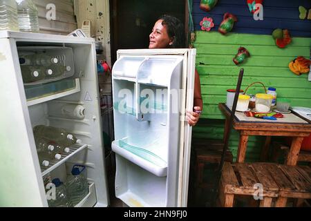 Eine Frau öffnet ihren beschädigten Kühlschrank, wo sie nur Trinkwasser in ihrem Haus aus Zing Laken im Viertel La Pastora am Montag, den 14. Februar 2022 in Maracaibo, Venezuela, aufbewahrt. Die Pandemie Covid-19 und die Brennstoffkrise haben die wirtschaftliche Situation verschärft, die dieses Land, das reich an Ölvorkommen ist, seit Jahren erlebt. Nach den Ergebnissen einer Studie der Katholischen Universität Andrés Bello (UCAB). Seit 2014 leidet das Land unter einem Mangel an grundlegenden Dienstleistungen wie Trinkwasser, Strom, Gas, Arbeitslosigkeit, Hyperinflation und den ständigen Abwertungen Stockfoto