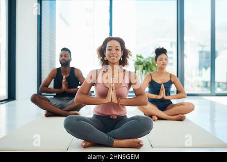 Wir machen das wirklich einfach. Portraitaufnahme einer jungen, fit getrampten Gruppe von Menschen, die eine Yoga-Pose auf dem Boden in einem Studio machen. Stockfoto