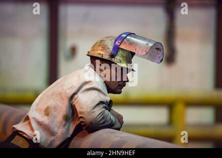 Temirtau, Kasachstan - 08. Juni 2012: Metallurgie-Anlage von Arcelor Mittal. Stahlherstellung. Portrait eines erwachsenen Metallurgen in schmutzigem weißem Hardhut und Stockfoto