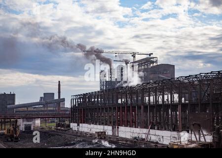 Blick auf die moderne Schmelzerei. Rauchschächte, Industriegebäude, Krane. Stahlkonstruktion im Vordergrund. Stockfoto