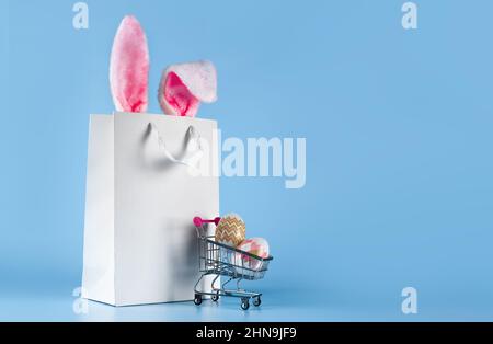 Die Idee der Lieferung von Einkäufen zu Ostern nach Hause, auf blauem Hintergrund Stockfoto