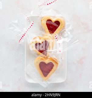 Linzer-Kekse mit Himbeer-Füllung in Zellophan zum Valentinstag. Stockfoto