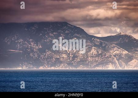 Panorama des berühmten heiligen Berges Athos mit Klöstern in Griechenland. Blick auf den Sonnenuntergang von der Halbinsel Sithonia in Chalkidiki. Wallfahrt und religiöse w Stockfoto