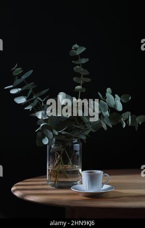 Tasse Kaffee und ein paar Eukalyptus auf einem Holztisch. Speicherplatz kopieren Stockfoto