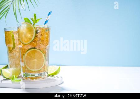 Cuba Libre, langer Eisteecocktail mit starkem Alkoholgetränk, Cola, Limette und Eis in zwei Gläsern, kalter Longdrink-Mocktail auf hellblau gefliestem Rücken Stockfoto