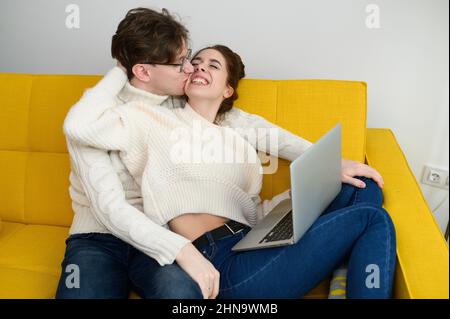 Porträt eines lächelnden jungen Paares mit Laptop zu Hause indoor Stockfoto