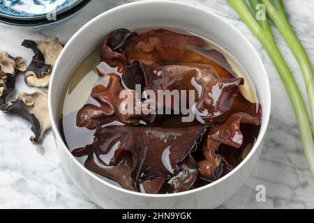 Getrocknete juden ohren Pilze, die in Wasser in einer Schüssel aus nächster Nähe einweichen Stockfoto