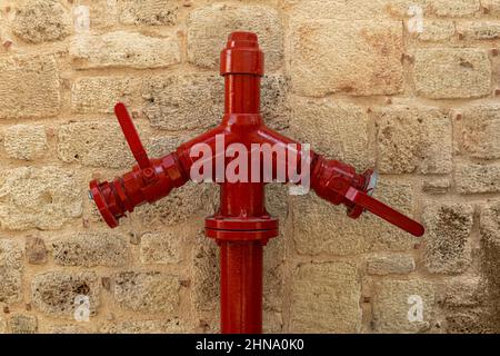 Roter Hydrant in der Nähe der alten Steinwand Stockfoto