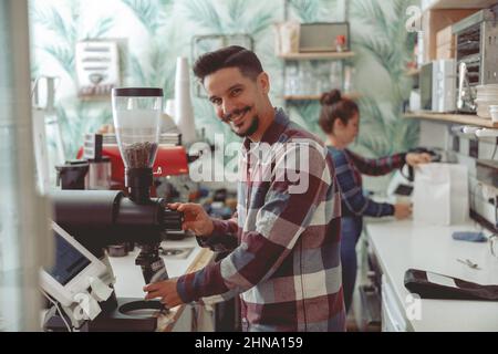Barista, der im Café in der Nähe der Kaffeemühle arbeitet Stockfoto