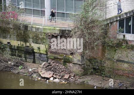 Salford, Großbritannien, 15th. Februar 2022. Ein Teil einer Ufermauer ist in der Nähe der Blackfriars Bridge in Salford, Greater Manchester, England, Großbritannien, in den Fluss Irwell eingestürzt. Auf dem Fußweg über dem Kollaps wurden Absperrbarrieren errichtet, aber einige Menschen ignorieren die Schließung und nutzen den Fußweg trotz des Sicherheitsrisikos immer noch. Quelle: Terry Waller/Alamy Live News Stockfoto