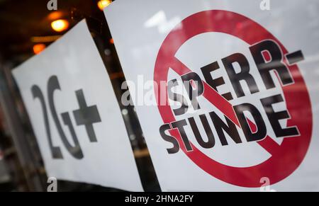 Hamburg, Deutschland. 15th. Februar 2022. Am Eingang einer Bar auf der Reeperbahn hängen ein Schild aus einer Kampagne zur Abschaffung der koronabezogenen Ausgangssperre und ein "2 G-Schild". Der rot-grüne Senat will die koronabedingte Ausgangssperre in der Gastronomie abschaffen, voraussichtlich am Wochenende. Quelle: Christian Charisius/dpa/Alamy Live News Stockfoto