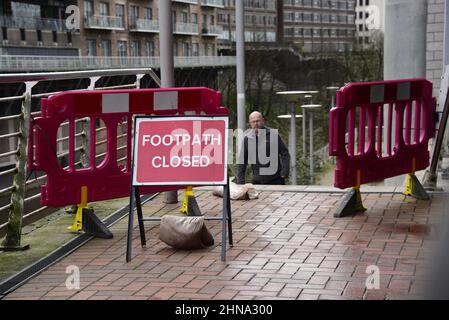 Salford, Großbritannien, 15. Februar 2022. Ein Teil einer Mauer am Flussufer ist in den Fluss Irwell in der Nähe der Blackfriars Bridge in Salford, Großbritannien, eingestürzt. Auf dem Fußweg über dem Einsturz wurden Schranken aufgestellt, aber einige Menschen ignorieren die Schliessung und benutzen den Fußweg trotz des Sicherheitsrisikos immer noch. Kredit: Terry Waller/Alamy Live News Stockfoto