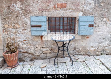 Stillleben mit Tisch und Fenster an der alten Steinfassade des Hauses, Rovinj, Kroatien, Europa. Stockfoto