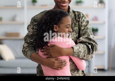 Nahaufnahme eines afroamerikanischen Mädchens, das ihren Vater Soldat umarmt Stockfoto