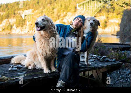 Fröhliche Hündin, die mit Hunden auf einem Picknicktisch sitzt Stockfoto