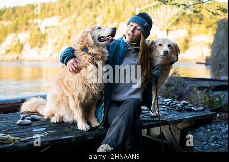 Fröhliche Hündin, die mit Hunden auf einem Picknicktisch sitzt Stockfoto