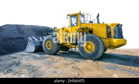 Gelber Radbagger, der einen Haufen Kies in einem Steinbruch bewegt, der auf weißem Hintergrund isoliert ist Stockfoto