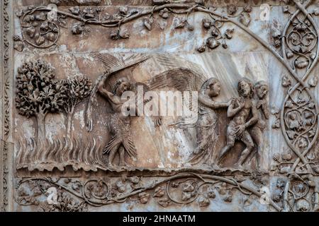 Engel vertreiben Adam und Eva aus dem Paradies in den 1300er Jahren Hebräische Bibel / Altes Testament Marmor Basreliefs an der Westfront der Kathedrale von Orvieto, Umbrien, Italien. Diese Skulptur wird Lorenzo Maitani (ca. 1275–1330) zugeschrieben, der die spätgotische Fassade der Kathedrale entwarf. Maitani soll als Bildhauer direkt auf zwei Tafeln eingegangen sein, die zwei der vier unteren Pilaster der Fassade bedecken: Eine Platte zeigt Szenen aus der hebräischen Bibel/dem Alten Testament, einschließlich der Szene in diesem Bild. Stockfoto