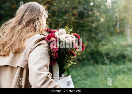 Mädchen mit einem Blumenstrauß von hinten im Park Stockfoto