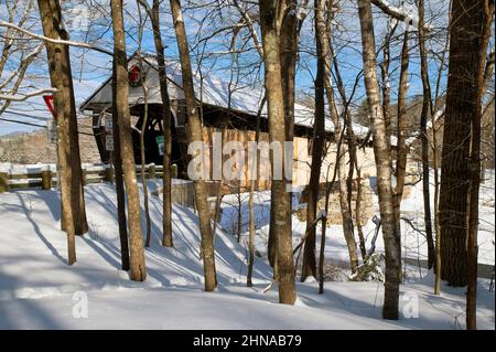 Die Blair Covered Bridge aus der Sicht durch Bäume (1869) in Campton, New Hampshire, USA, an einem Wintertag Stockfoto