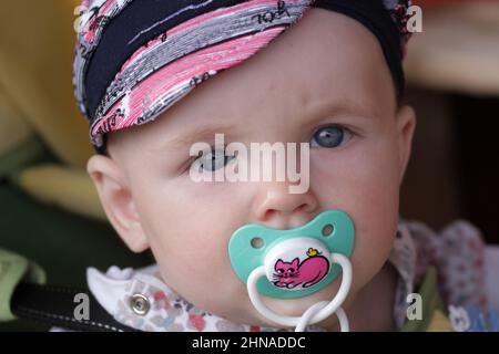 Das ernsthafte Baby posiert mit einem Schnuller Stockfoto
