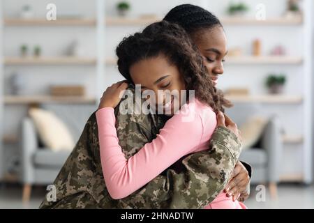 Seitenansicht der Mutter in militärischer Uniform umarmt Kind Stockfoto