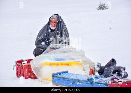 Gulmarg, Indien. 15th. Februar 2022. Ein Anbieter wartet während eines Schneefalls in Gulmarg, Kaschmir, auf Kunden. Kredit: SOPA Images Limited/Alamy Live Nachrichten Stockfoto