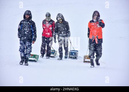 Gulmarg, Indien. 15th. Februar 2022. Kashmiri-Männer werden während eines Schneefalls in Gulmarg, Kaschmir, mit Schlitten wandern gesehen. Kredit: SOPA Images Limited/Alamy Live Nachrichten Stockfoto