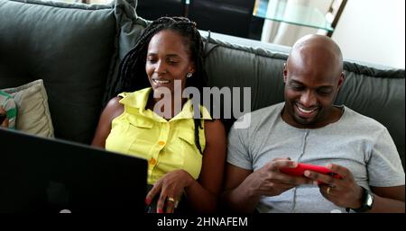afroamerikanische Ehemann und Ehefrau haben ein ehrliches Gelächter. Ehemann und Ehefrau lächeln mit Computer und Technik Stockfoto