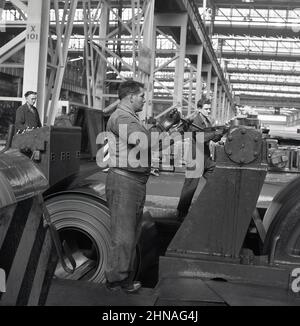 1950s, historisch, Arbeiter in einer Industriefabrik, die gewalzte Stahlbleche pressen, Port Talbot, Wales, Großbritannien. Stockfoto