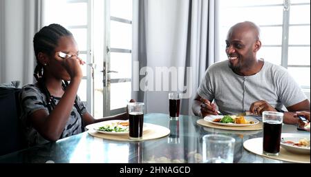 Schwarzer Vater und Tochter lachen beim Mittagessen Stockfoto