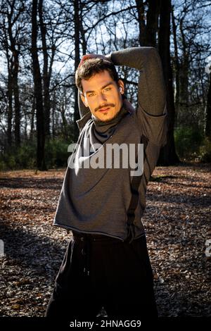 Läufer streckt sich beim Musikhören. Der junge Mann bildet im Wald aus. Konzept von Sport und Wellness. Stockfoto