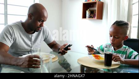 Vater telefoniert während der Mittagszeit, schwarzafrikanische Familie isst Stockfoto