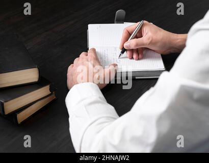 Anwälte Hände Notizen in Planer. Mit Büchern, Codes auf dem Schreibtisch. Geschäfts- und Bildungskonzept . Hochwertige Fotos Stockfoto