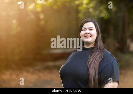 Eine brünette Frau in einem schwarzen Hemd mit langen Haaren, die draußen stehen Stockfoto