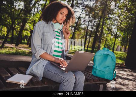 Profil Seitenfoto der jungen afrikanischen Frau konzentriert nachdenklich schauen Laptop-Suchmaterialien im Freien Stockfoto