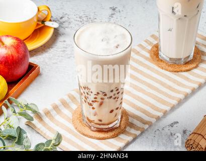 Pearl Milk Tea Boba / Bubble Tee im Glas auf Matte mit grauem Hintergrund Frühstücksgetränk Stockfoto