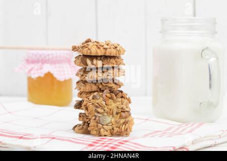 Süße Kekse und Milch mit Honig auf einem hölzernen Hintergrund. Hintergrund mit Kopierbereich Stockfoto