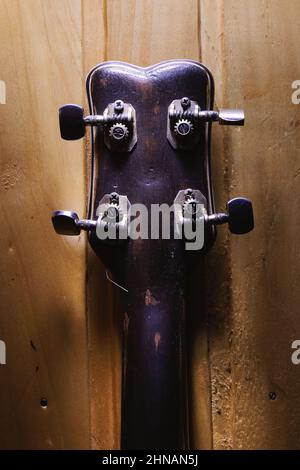 Details einer kleinen Gitarre mit vier Saiten, Hinterteil eines Kopfes und Pins. Stockfoto