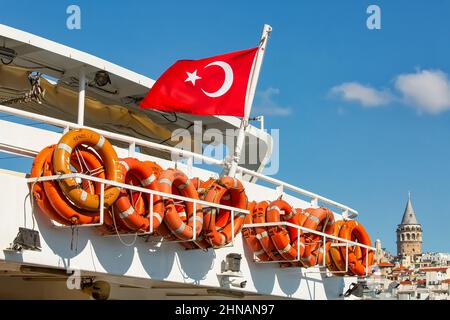 ISTANBUL, TÜRKEI - 9th. Oktober 2019: Türkische Flagge und Rettungsschwimmer an Bord eines Schiffes, Galata Tower im Hintergrund Stockfoto