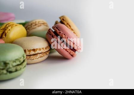 französische Kuchenmakronen und Frühlingsblumen auf weißem Hintergrund Stockfoto