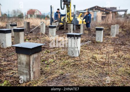 Foundation arbeitet mit Bohrpfahlanlage auf der Baustelle, Arbeiter fahren einen Haufen in der Erde Stockfoto