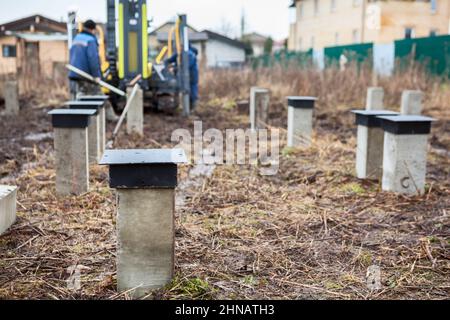 Betonpfahlbohrung mit mechanischem Peilfluss, Fundament für Holzrahmenhaus, ebenerdrige Ebene Stockfoto